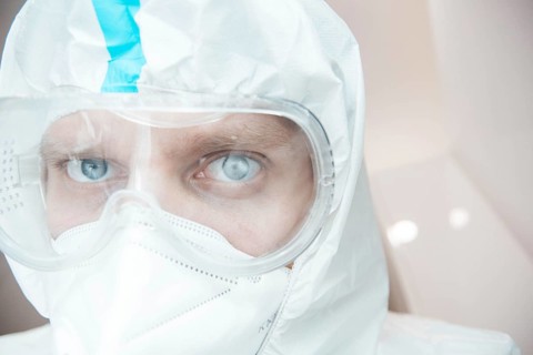Medical laboratory assistant in a chemical protection suit and safety glasses
