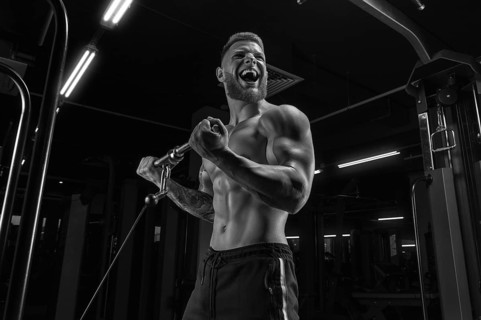 Portrait of an athlete pumping biceps in a crossover. Bodybuilding and fitness concept.