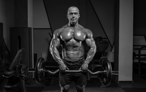 Professional weightlifter posing in the gym with a barbell in his hands. Classic bodybuilding.