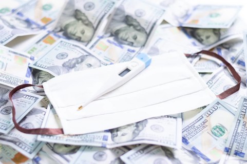 Medical mask and a thermometer lie on one hundred dollar bills. The concept of an epidemic