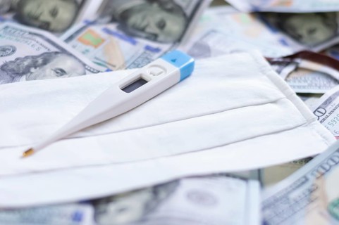 Medical mask and a thermometer lie on one hundred dollar bills. The concept of an epidemic