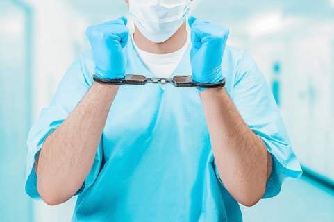 Portrait of a doctor in handcuffs. The concept of corruption in medicine.