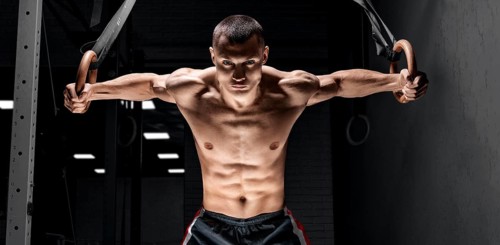 The athlete pulls himself up on the gymnastic rings. The concept of sport and healthy lifestyle.