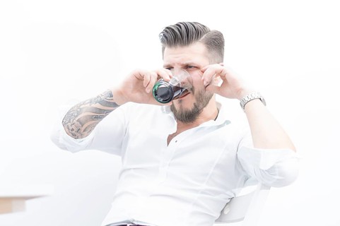 Stylish man sits on a chair and gets drunk with rum and cola. The concept of unsuccessful business