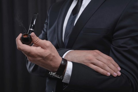 Image of male hands holding a smoking pipe. Tobacco smoking concept.