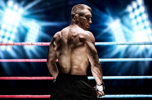 Portrait of a kickboxer on the background of bright spotlights. Back view. The concept of sports and mixed martial arts.