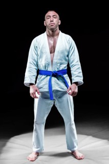 Professional athlete stands in the gym in a kimono with a blue belt. Concept of karate