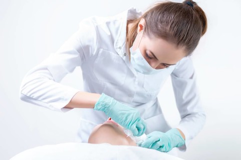 The beautician washes the patient's face before peeling. Skin care concept.