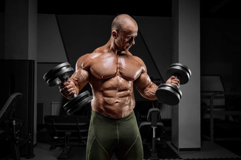 Professional weightlifter is training in the gym. Dumbbell Curl. Bodybuilding concept.