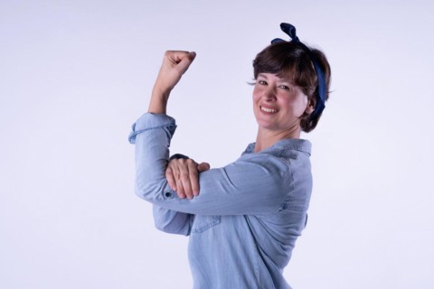 Short-haired girl showing strong arm muscle isolated. Concept WomenÂ´s day. Copy space. Portrait isolated on white background