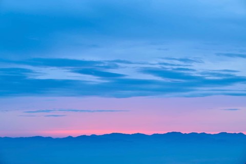 Dawn with pink and blue colours over a mountainous silhouette