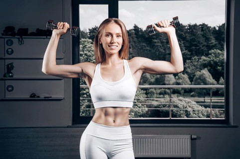 Charming young athlete is training with dumbbells in the gym. Bodybuilding concept. Sport. Weightlifting.