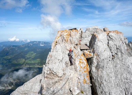 Female mountaineer climbing a via ferrata secured with a steel cable