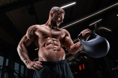 Muscular man posing in the gym with a kettlebell. Fitness concept.