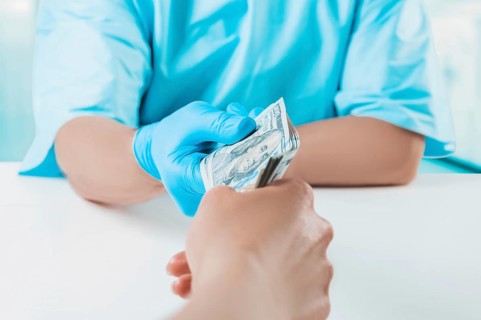 The girl gives the doctor a pack of hundred-dollar bills. Medicine concept.