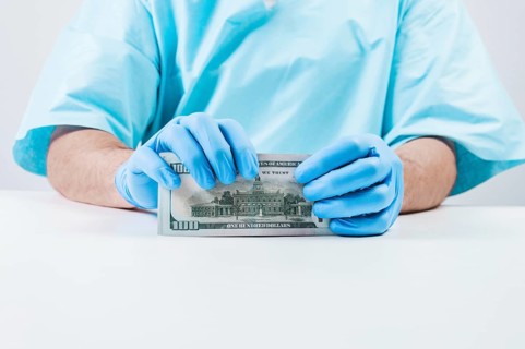Doctor holds one hundred dollar bills. The concept of corruption in medicine.