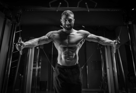 Muscular athlete training in a crossover at the gym. Pumping the torso. Fitness and bodybuilding concept.