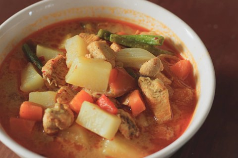 A bowl of hearty chicken curry with potatoes and carrots