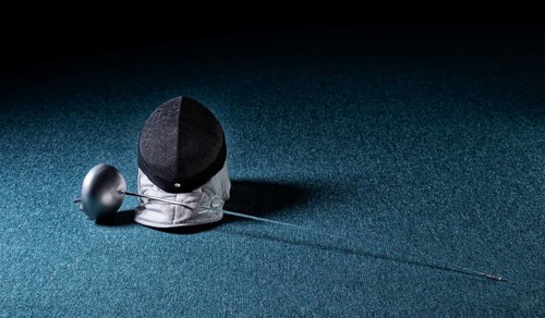 The sword and mask lie on a blue background. The concept of fencing.