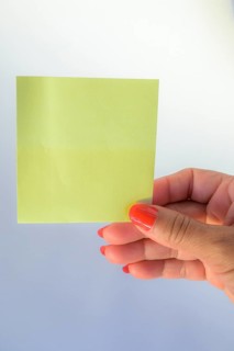 Woman's hand with painted nails holding blank letter paper on pure white background