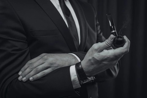 Image of male hands holding a smoking pipe. Tobacco smoking concept.