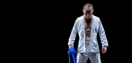 Professional athlete stands in the gym in a kimono with a blue belt. Concept of karate