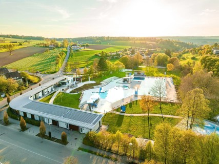 Wide-angle drone shot of an outdoor swimming pool in a rural area during sunset