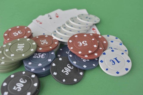 Stacks of poker chips and a fan of playing cards on a green felt gaming table