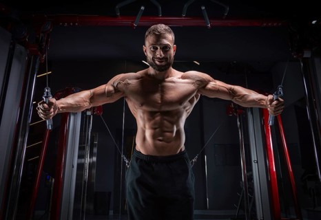 Muscular athlete training in a crossover at the gym. Pumping the torso. Fitness and bodybuilding concept.