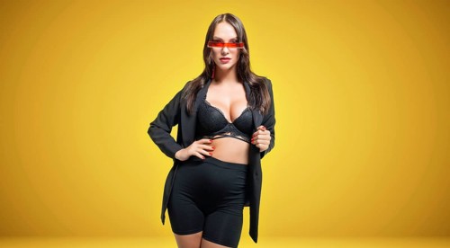 Beautiful tall pregnant brown-haired woman posing in the studio on a yellow background. Maternity lingerie concept.