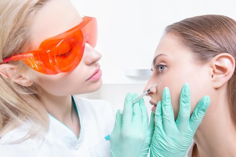 Portrait of the beautician and patient. The doctor injects botox. Skin rejuvenation and lifting concept.
