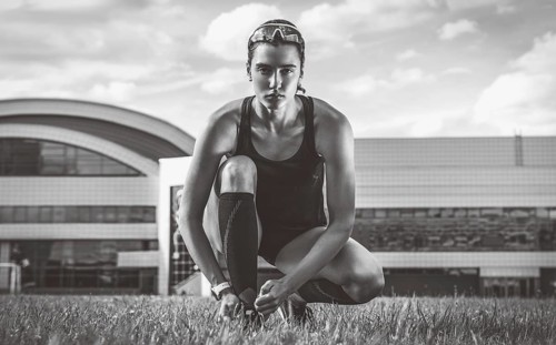 Portrait of a young runner who laces her boots at a football stadium. Sports concept.