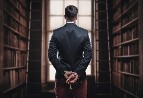Portrait of an elegant man in a suit in the library. Back view. Business concept.