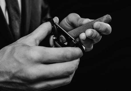 Image of hands holding a guillotine and a cigar. Cigar clubs concept.