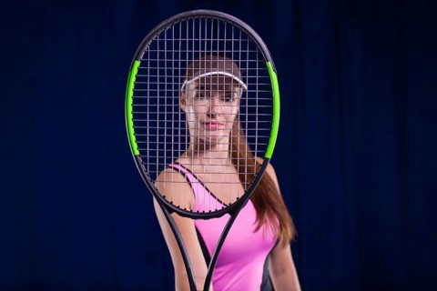 Portrait of a beautiful tennis player in a pink dress on the court. Sports concept.