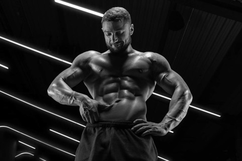 Portrait of an athletic muscular man who checks the condition of the abdominal muscles. Fitness concept.