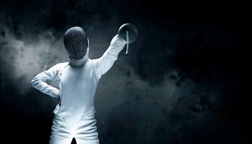 Charming girl dressed as a fencer posing with a mask and a sword. The concept of fencing.