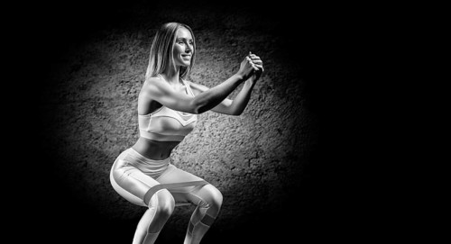 Charming girl is training in the gym with a rubber band. The concept of bodybuilding