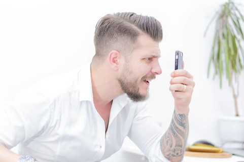 Man in a shirt looks at the smartphone screen in surprise. Concept of unsuccessful betting on games