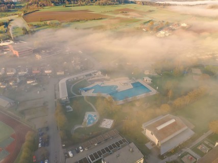 A swimming pool surrounded by fog at dawn