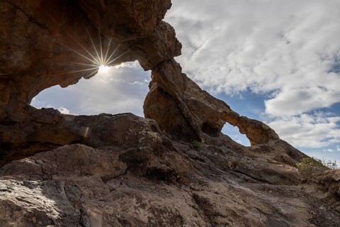 Sun shining through stone arches in volcanic rock