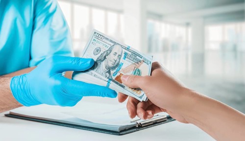 The girl gives the doctor a pack of hundred-dollar bills. Medicine concept.