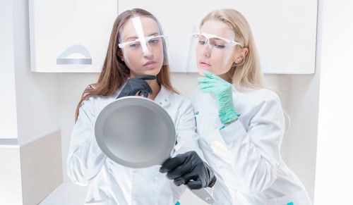 Two beauticians pose in a medical salon with a mirror in their hands. Rejuvenation concept.