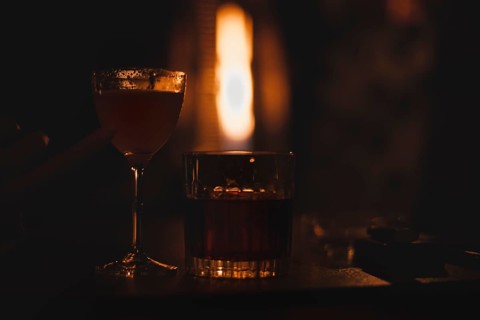 Image of a glass with a cocktail in a night bar against the background of a fiery heater. Restaurant concept