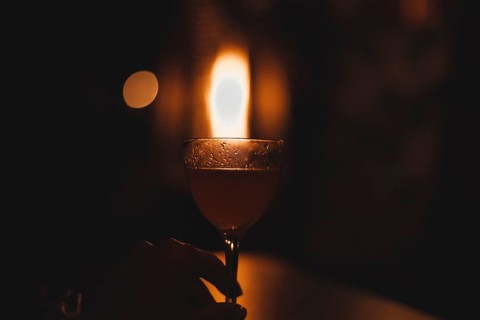 Image of a glass with a cocktail in a night bar against the background of a fiery heater. Restaurant concept