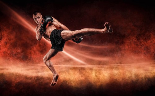 Professional kickboxer jumps with his knee extended. Fiery arena. Mixed martial arts. Sports concept