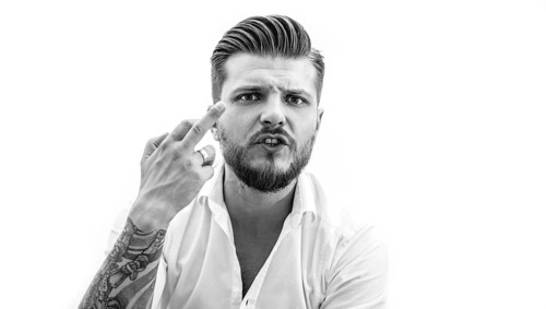 Stylish bearded man shows middle finger to the camera. The concept of failure