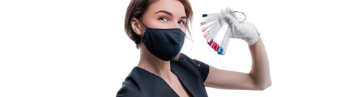 Portrait of an elegant beautiful girl wearing a protective mask with a set of nail palette in hand. White background. Advertising banner for beauty salons during Covid-19. Pandemic. Modern trends