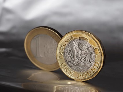 1 pound and 1 euro coin over metal background