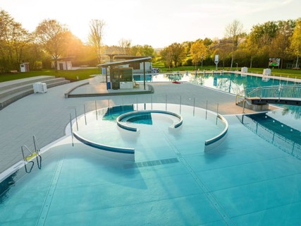 Overview of an empty outdoor pool with slide and sun-drenched pools